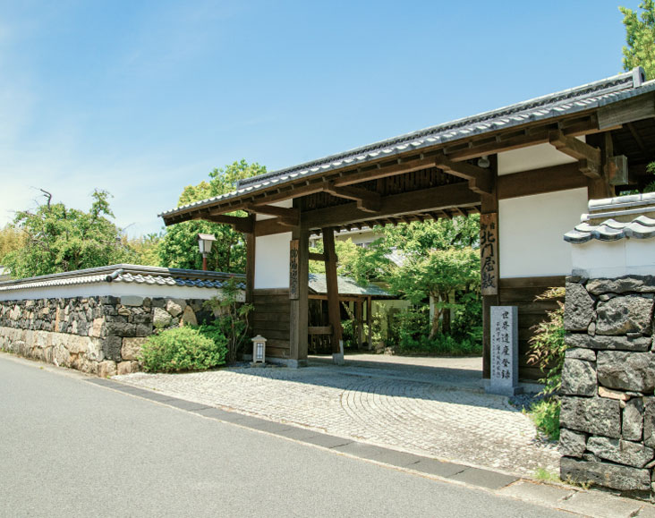 石積と白壁で作られた瓦屋根の塀で囲まれた北門屋敷の門