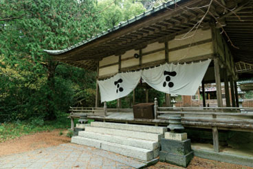 日本の伝統的な神社の拝殿。白い布に黒い紋が描かれている。