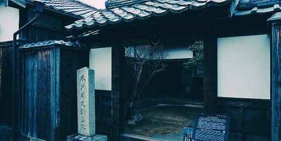 石橋と石碑が並ぶ、青空の下の歴史的な風景。