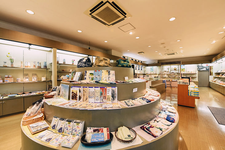 ハンカチや雑貨が整然と並ぶ、和モダンな雰囲気の土産物店の明るい店内