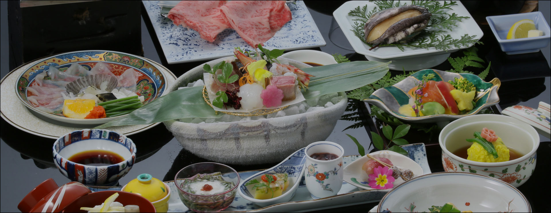あわびやふぐ刺し、すき焼きなど様々な料理が並んだ会席料理