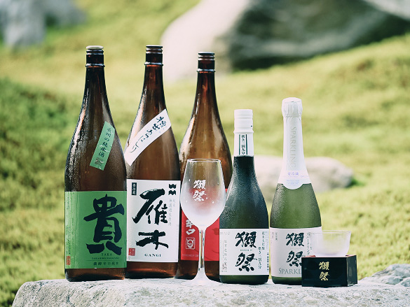 様々な種類の日本酒。茶色や緑色の瓶、ロゴ入りグラスと升。