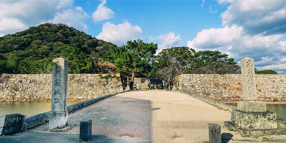 Stone bridges and stone monuments line the historic landscape under a blue sky.