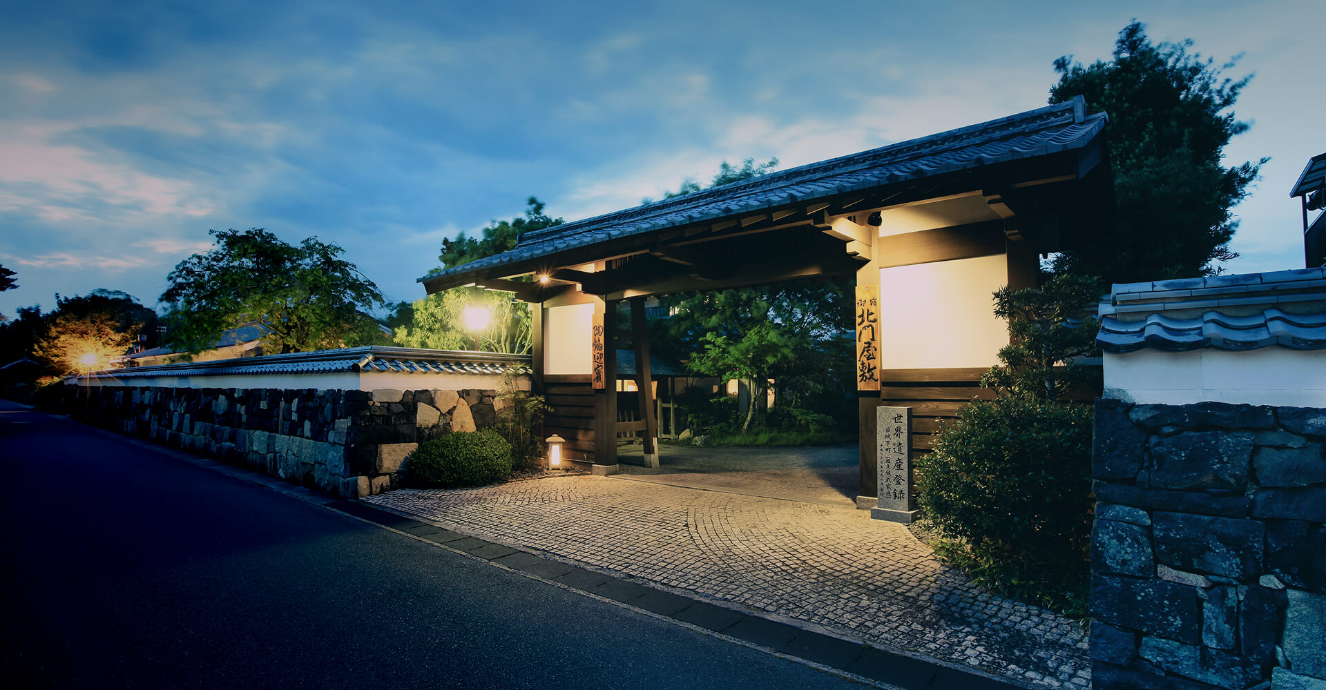 ライトアップされた石垣と生け垣に囲まれた北門屋敷の門