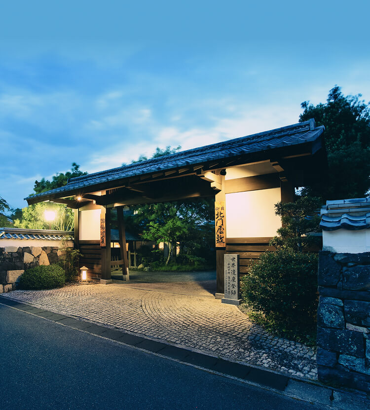 ライトアップされた石垣と生け垣に囲まれた北門屋敷の門