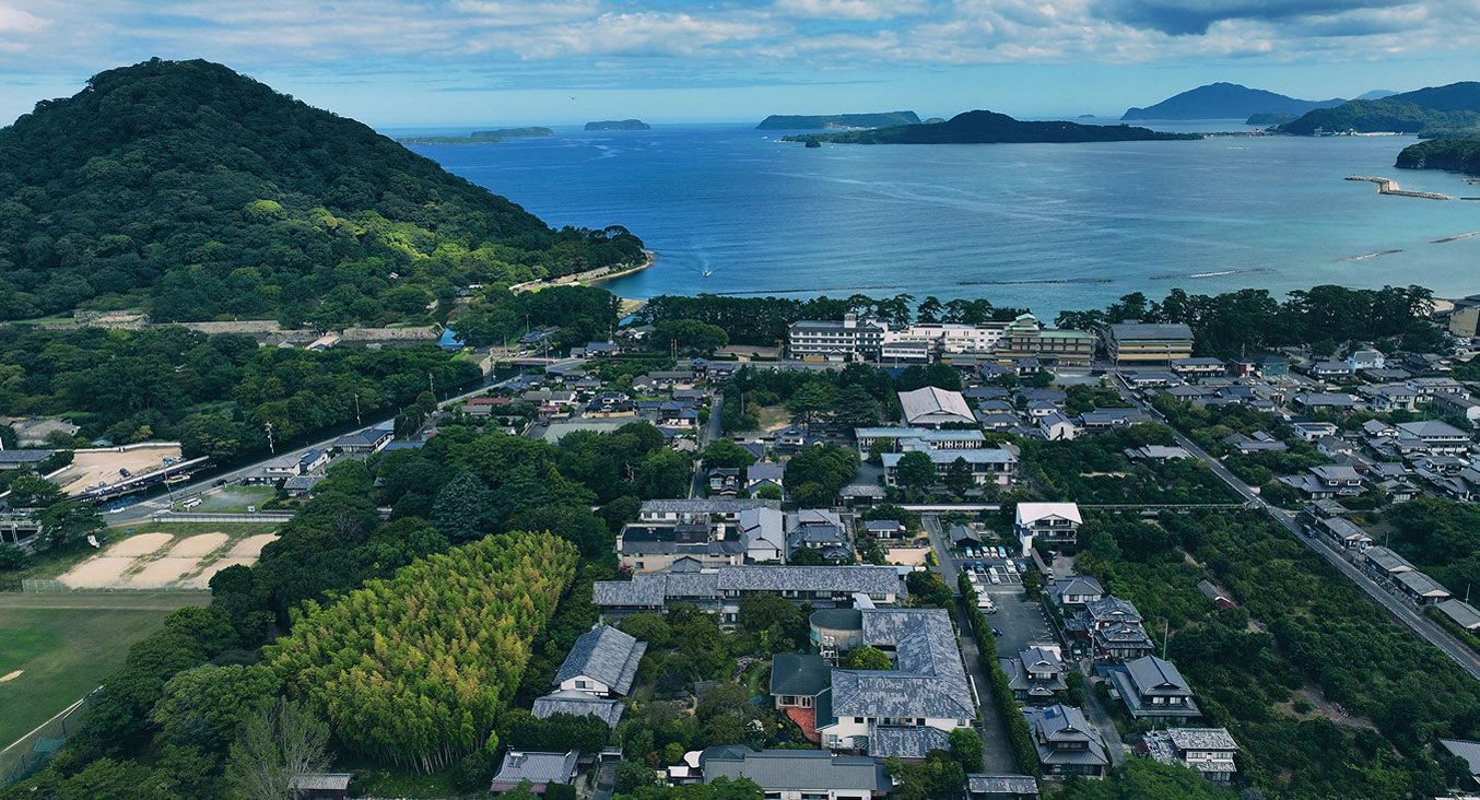 海と山に囲まれた街の全景を空撮した風景。