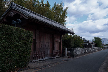 生け垣に囲まれた広い敷地にある木造の門。