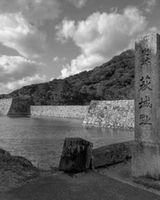 「萩城跡」と刻まれた石碑と、城下町の面影を残す山と石垣の景色。