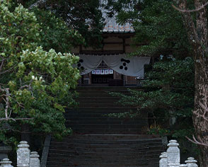 青々とした木々に囲まれた石段の先にたたずむ、趣ある神社の境内入口