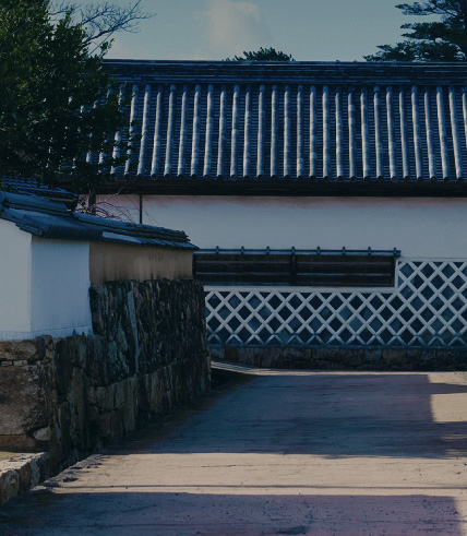 生け垣や昔ながらの白壁の建物が並ぶ道