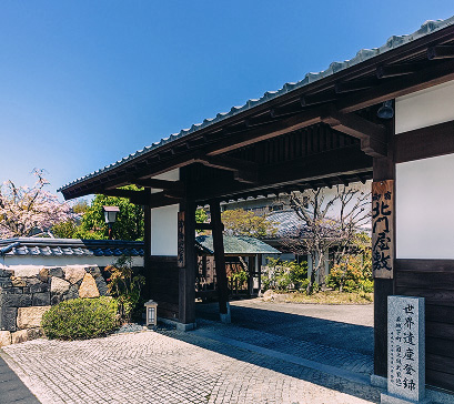 立派な木造の門構え。奥には庭園のような景色が見える。