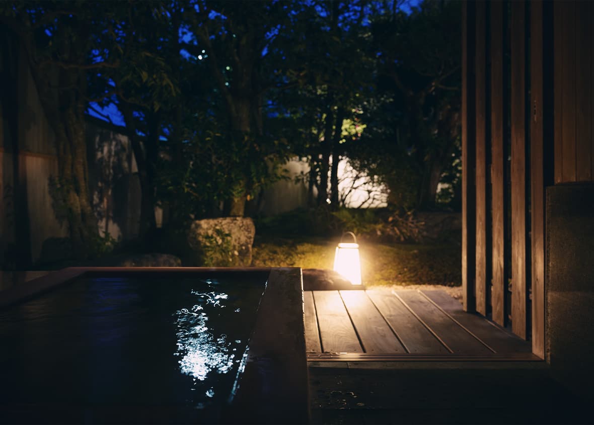 夜、ランタンの明かりに照らされた静かな露天風呂。